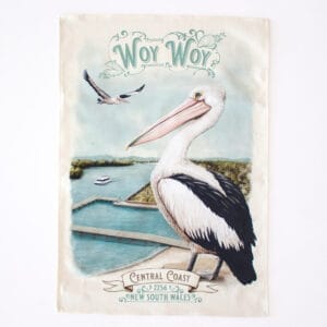 An illustrated tea towel featuring a pelican and the Woy Woy waterfront in the background